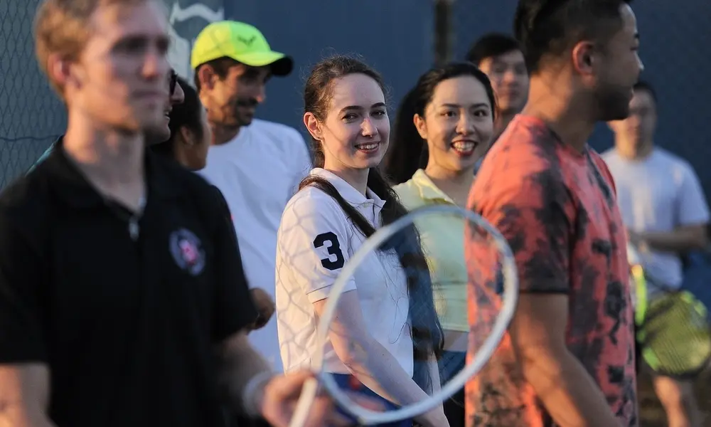 Students smiling on court during an evening group lesson