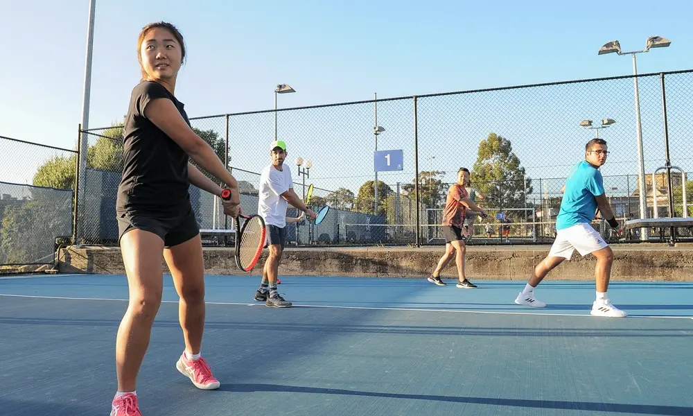 Hero — social play session with four players rallying on court 1